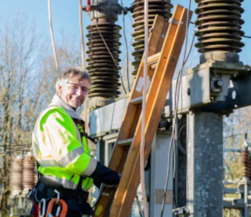 Dieses Foto zeigt einen Techniker welcher an einem Strommast steht