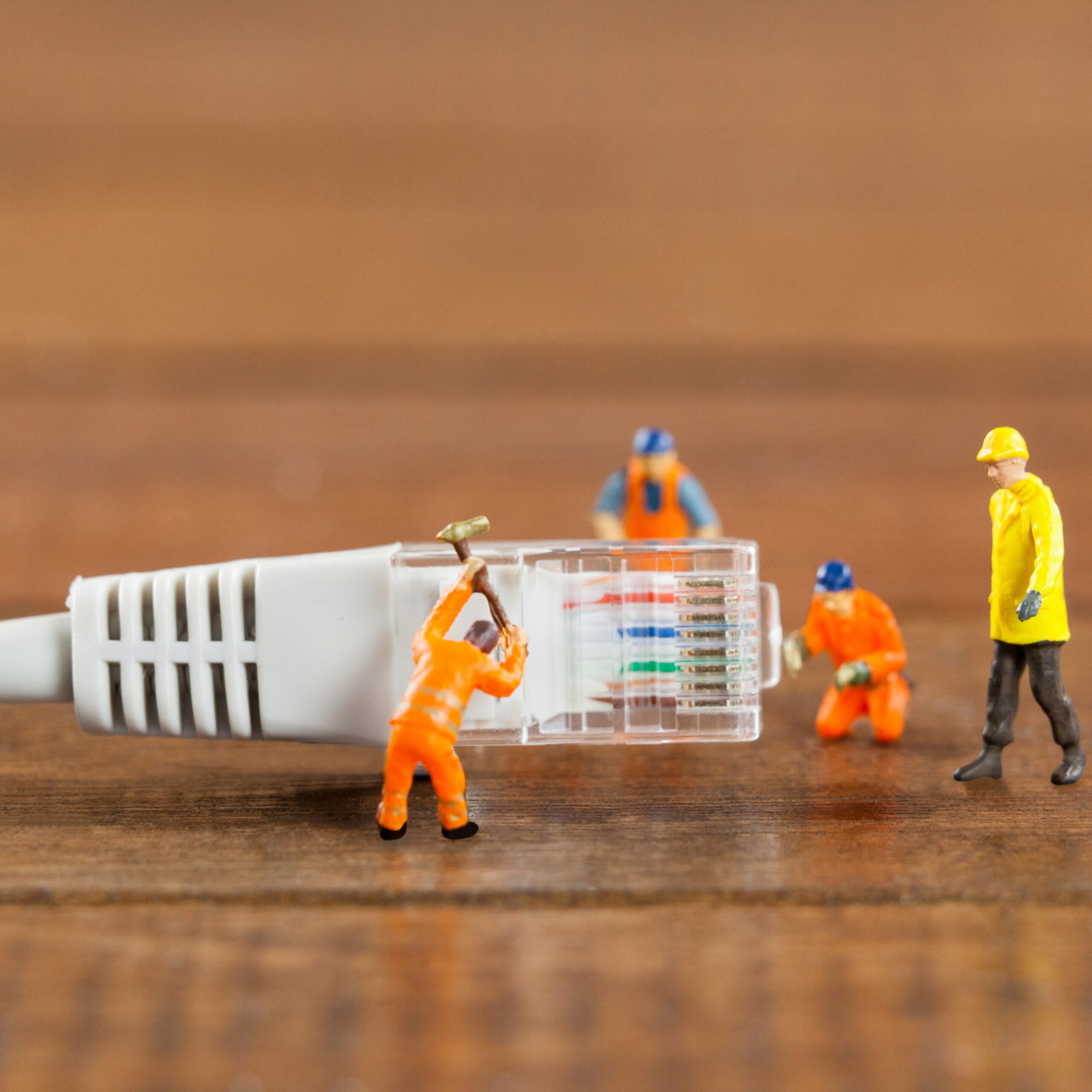 Ein Internet-Kabel an dem kleine Miniatur Figuren arbeiten